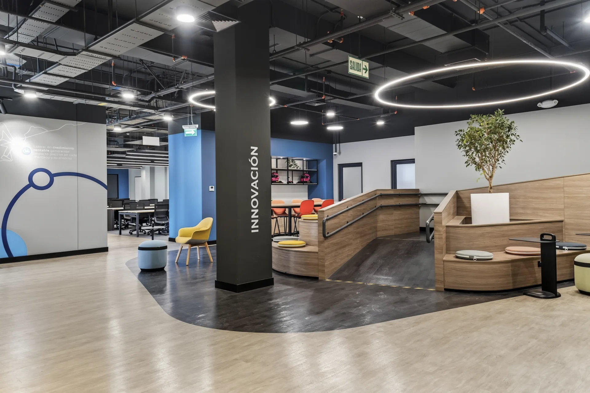 Espacio de innovación con graderías y luminarias circulares en las oficinas de Cencosud Miraflores